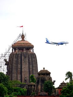 an airplane flying over the top of a large building with a dome on it's roof