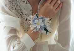 a woman wearing a white shirt and blue flower wrist corsage