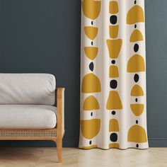 a chair sitting in front of a curtain with yellow and black shapes on it next to a gray wall