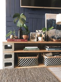 a living room with books, plants and pictures on the shelf next to the tv