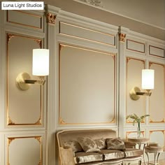 an elegant living room with gold trimmings and white walls, along with two couches