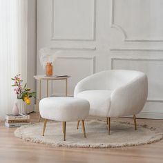 a white chair and footstool sitting on a rug in front of a window