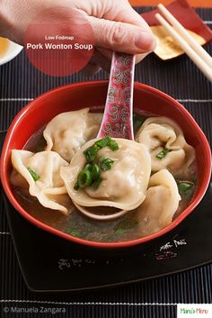 a person holding a spoon over a bowl of dumplings with chopsticks in it