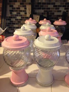 there are many pink and white candy jars on the counter