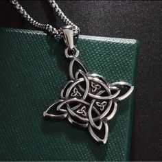 a celtic knot pendant on a green leather bag