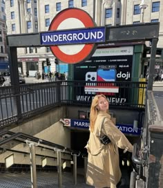 a woman standing in front of a underground sign