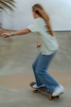 a young woman riding a skateboard on top of a cement floor next to palm trees