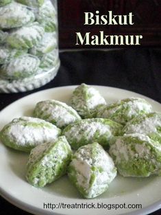 green and white powdered sugar cookies on a plate next to a glass jar with the words biskut makimur