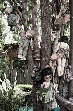 several stuffed animals hanging from the branches of trees in a yard with other stuffed animals on them