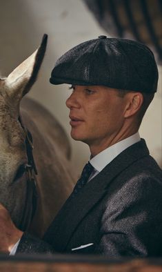 a man in a suit and hat standing next to a horse