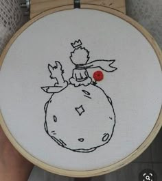 someone is holding up a cross - stitched picture of a bird on top of a round object