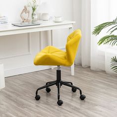 a yellow office chair sitting on top of a wooden floor next to a white desk