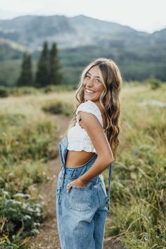 a woman wearing overalls and smiling at the camera