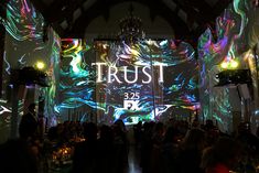 people are standing in front of an illuminated room with the words trust projected on it