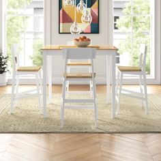 a dining room table with four chairs and a bowl of fruit on it