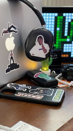 an apple computer sitting on top of a wooden desk next to a phone and headphones