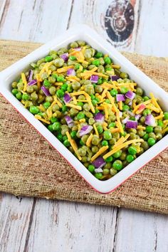 a bowl filled with peas and cheese on top of a table