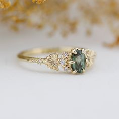 a close up of a gold ring with an oval green stone and diamond accents on it