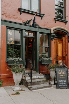 the front entrance of a restaurant with two large planters