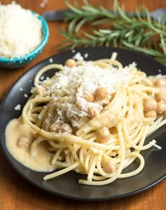 a black plate topped with pasta covered in sauce