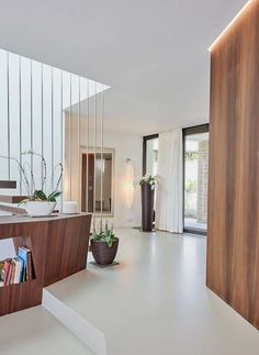 the interior of a modern home with white floors and wood accents on the walls, along with potted plants