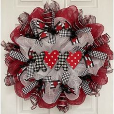 a red and white mesh wreath with two heart shaped bows on the front entrance door