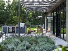 an outdoor kitchen and dining area is shown in this backyard garden scene with lavenders