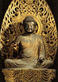 a golden buddha statue sitting in front of a black background