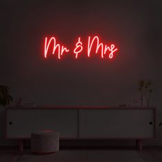 a red neon sign that says mr and mrs on the wall above a white cabinet