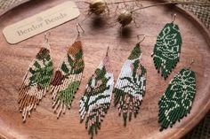 seed bead designs are displayed on a wooden tray