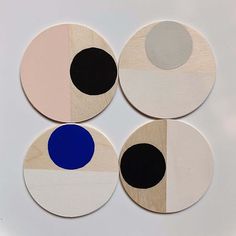 four circular wooden coasters with black, white, and blue circles on each one