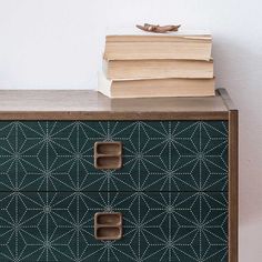 a stack of books sitting on top of a green dresser next to a white wall