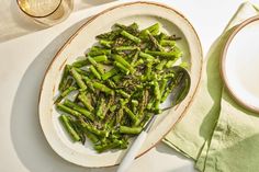 a white plate topped with asparagus next to a glass of wine and a spoon