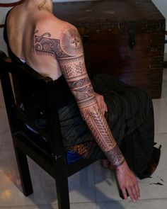 a man with a tattoo on his arm sitting in a chair