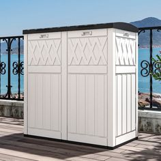 a large white storage shed sitting on top of a wooden deck next to the ocean