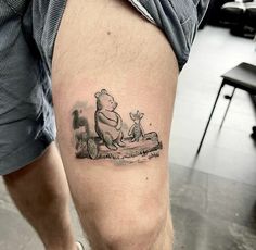 a man with a tattoo on his leg that has winnie the pooh and eebi