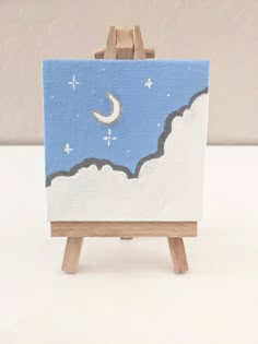 an easel with a painting on it and a moon in the sky behind it