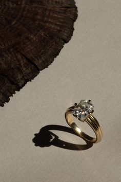 a diamond ring sitting on top of a table next to a piece of driftwood