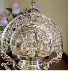 an ornately decorated silver plate sitting on top of a wooden table next to flowers