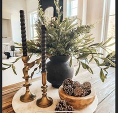 three candles are sitting on a table with pine cones