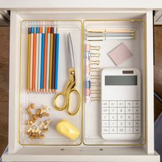 an organized desk drawer with pens, pencils, and calculator in it