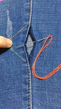 someone is stitching an orange string into the back pocket of a pair of jeans