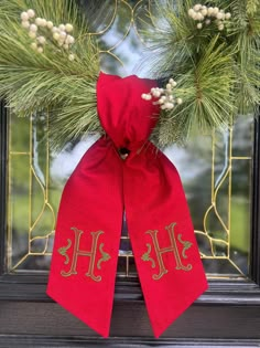 a christmas wreath with two monogrammed initials on it and a red bow hanging from the front door