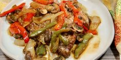 a white plate topped with meat and veggies on top of a wooden table