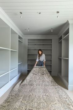 a woman standing on top of a large rug in a room filled with bookshelves