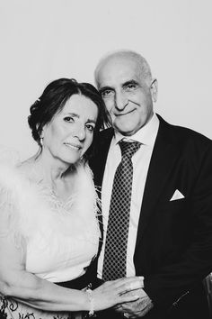 an older man and woman pose for a photo in black and white, smiling at the camera with their arms around each other