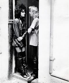 black and white photograph of two women standing in an open doorway, one looking at the other