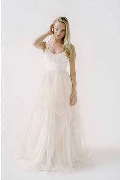 a woman in a white dress posing for the camera with her hand on her head