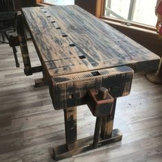 an old wooden table sitting on top of a hard wood floor next to a window