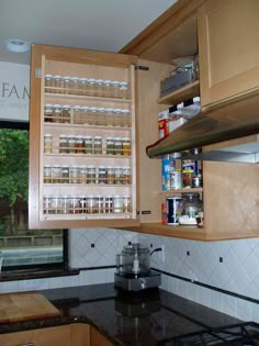 a kitchen with wooden cabinets and black counter tops next to an open window overlooking the trees